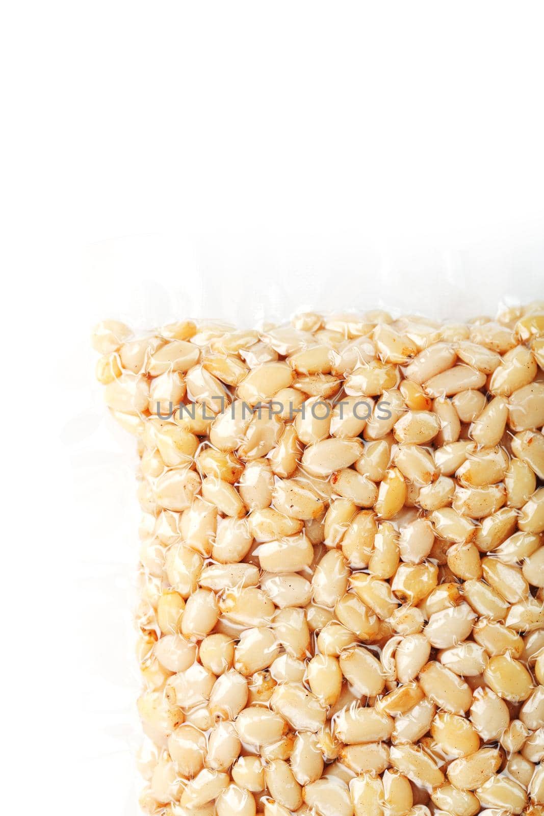 Kernels of peeled pine nuts in vacuum packaging on a white background with free space