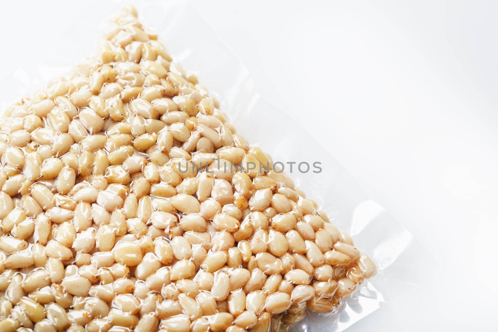 Pine nuts in a transparent vacuum package over a white background