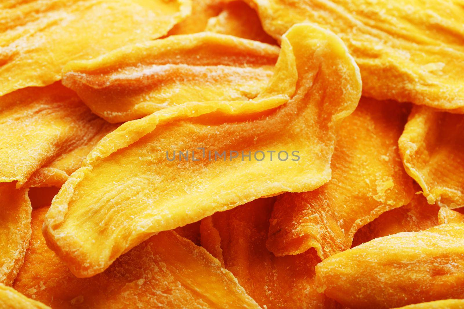 Dried sweet mango fruit slices as textural orange background in full screen