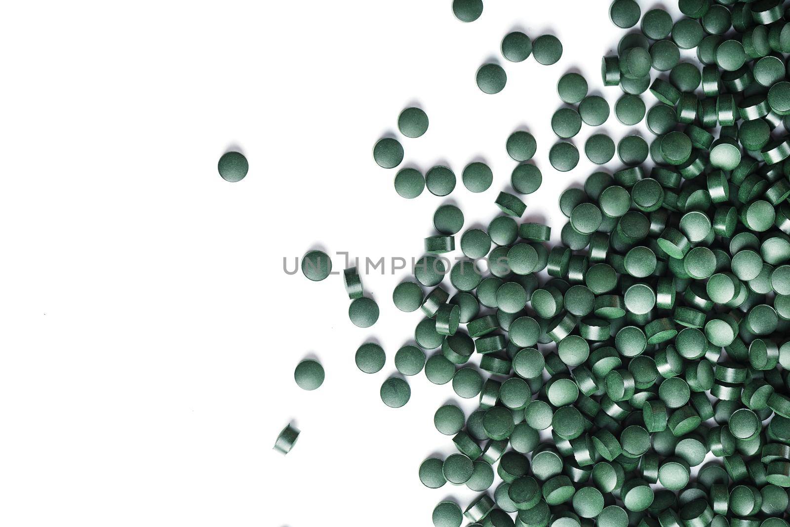 Vegetarian vitamins from Spirulina are scattered on a white background with free space