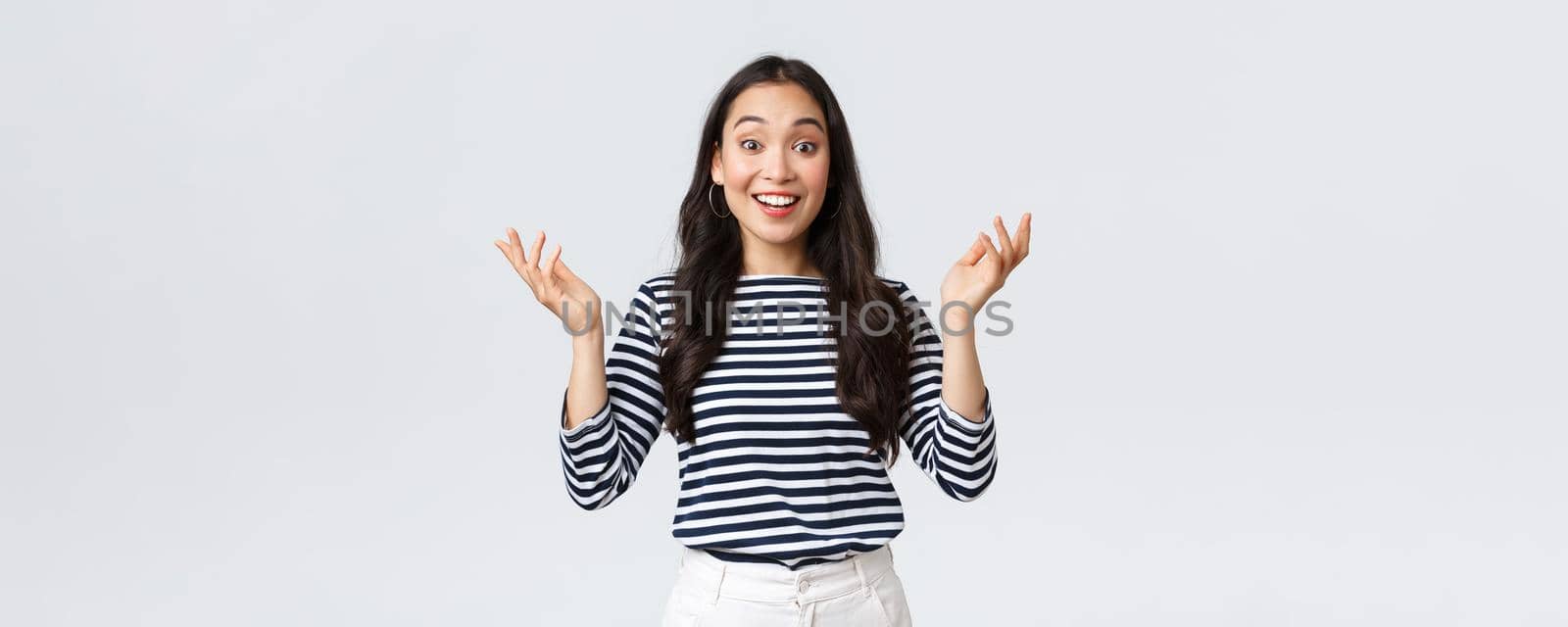 Lifestyle, beauty and fashion, people emotions concept. Surprised and amazed happy smiling asian woman find out perfect news, raise hands up astonished, congratulating or praising friend.