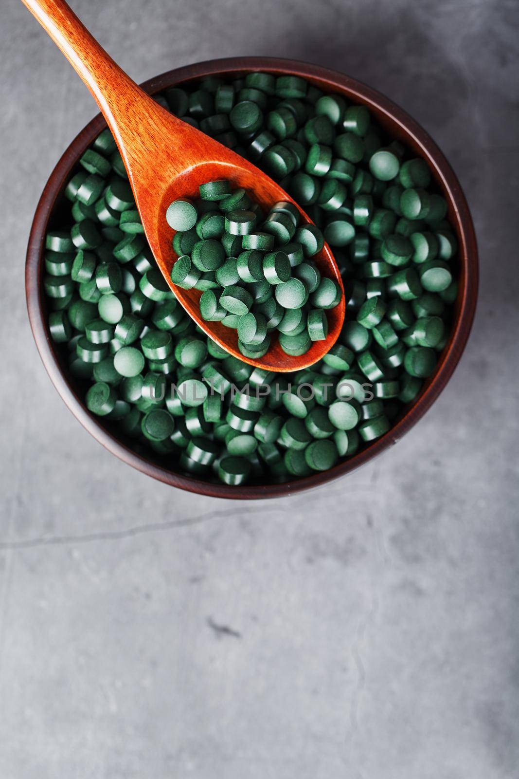 Vitamins from spirulina in a wooden cup with a wooden spoon on a dark background. Vegetarian source of amino acids and omega 3