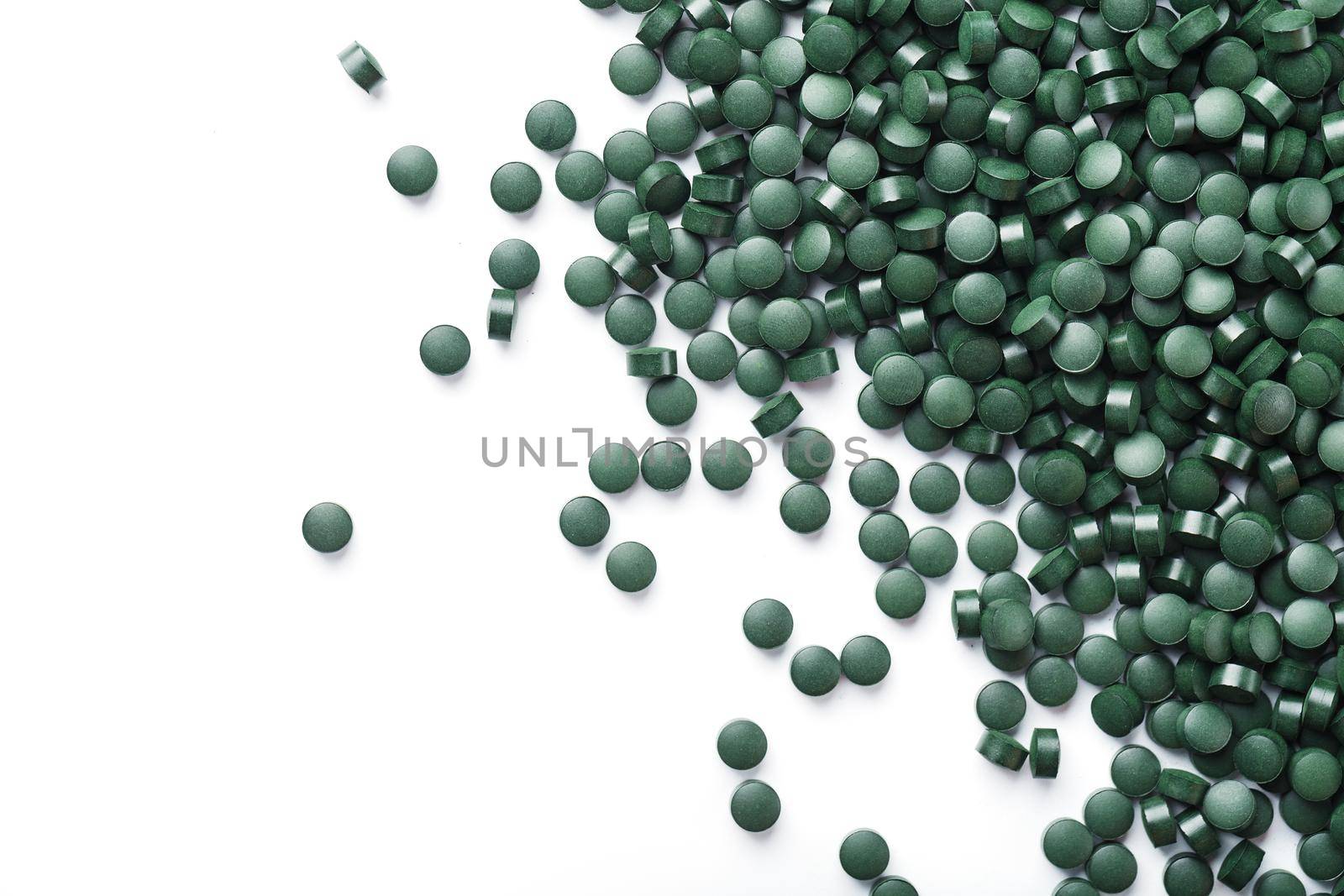 Vegetarian vitamins from Spirulina are scattered on a white background with free space