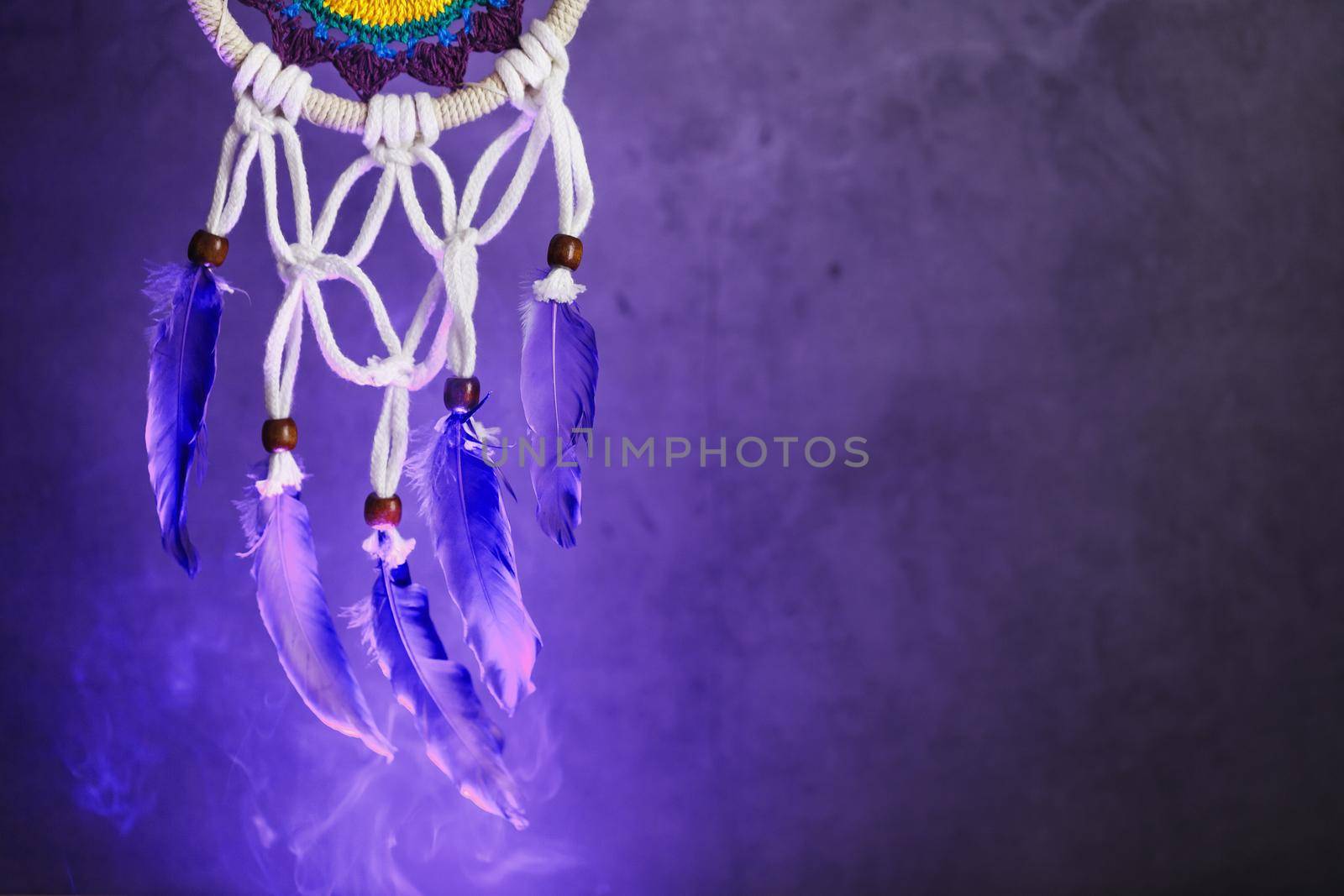 Dream catcher on a dark background with smoke and aquamarine light. Free space for text
