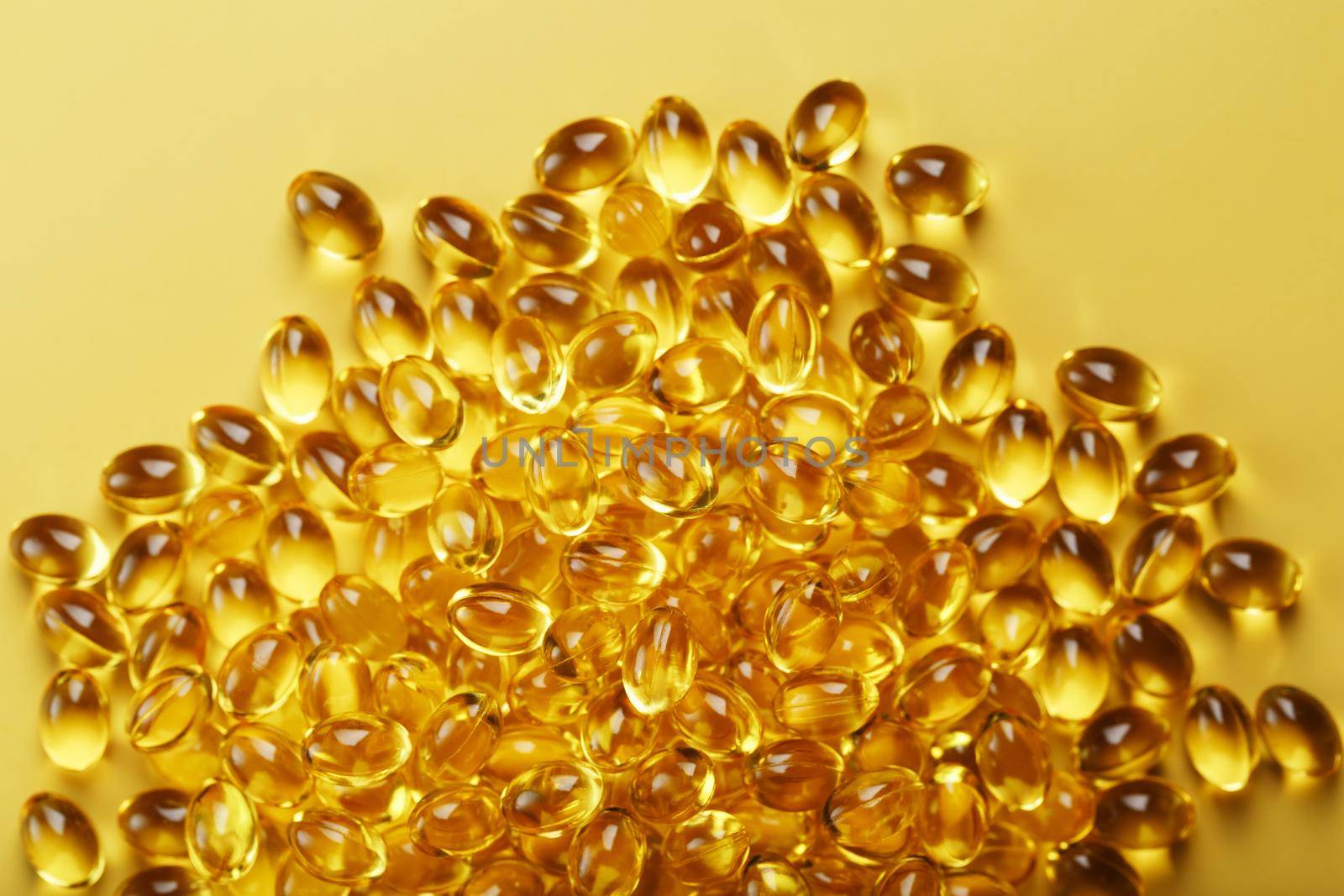 The texture of the capsules in the shell with liquid vitamin D3 in full screen. Gold capsules with a dietary supplement for joints teeth and bones.
