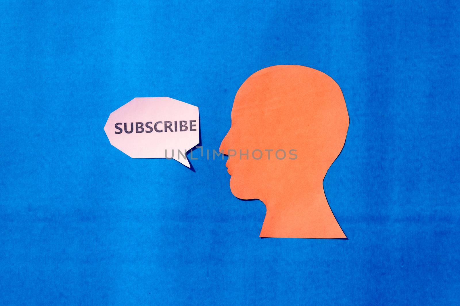 Paper Human face with Subscribe word on speech bubble isolated on blue background. Copy Space for text. by sudiptabhowmick