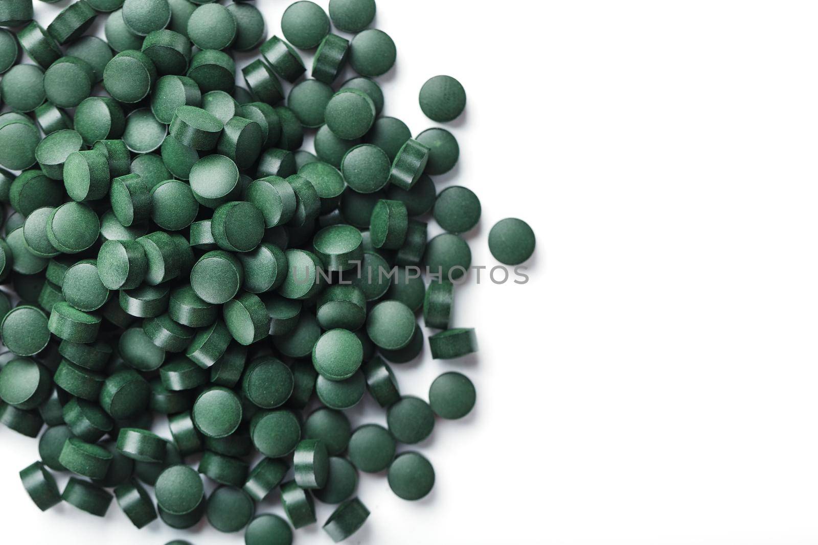Vegetarian vitamins from Spirulina are scattered on a white background with free space