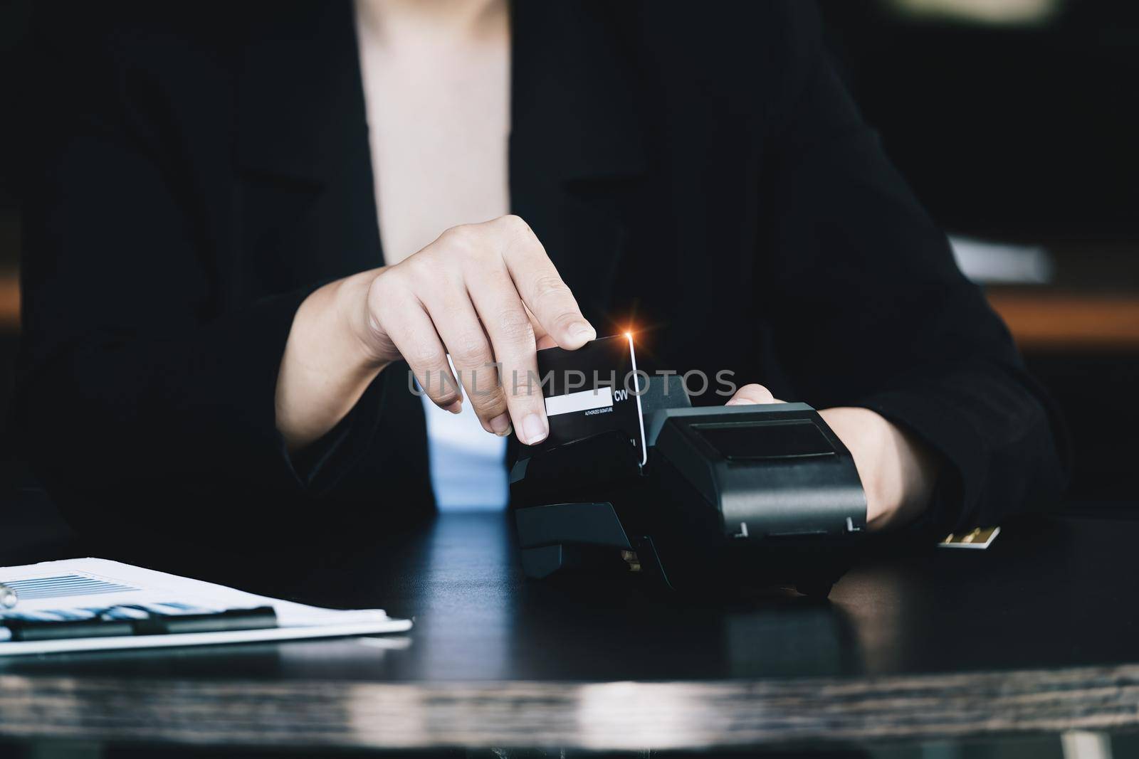 Safe technology concept from using credit card, employee is holding customer's credit card to pay for service or payment via electronic card swipe machine. by Manastrong