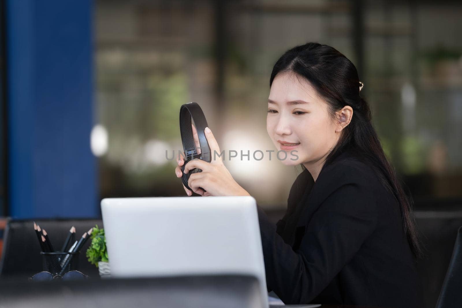 Concept of taking a break from work, an accountant or a female company employee or a business owner is using headphones to listen to music to relieve stress and fatigue from work