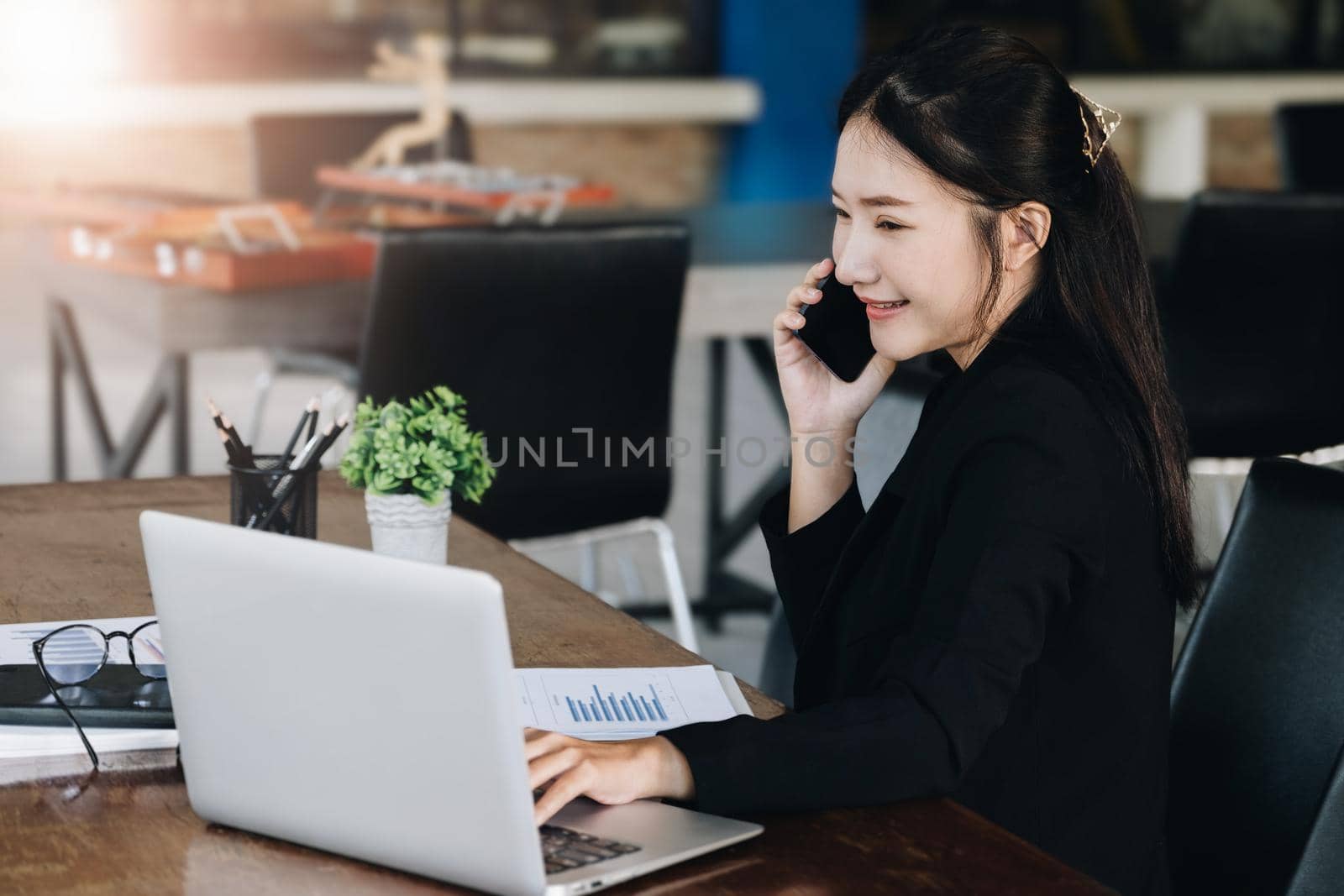 A female business woman is using the telephone to communicate with colleagues for financial planning and investment planning