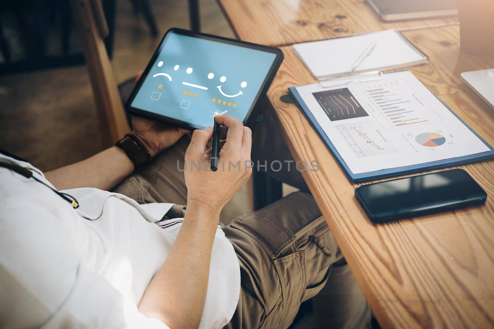 Quality and satisfaction rating concept, business men are using tablets to assess their 5-star satisfaction because their investment company's fund management is effective in managing their finances. by Manastrong