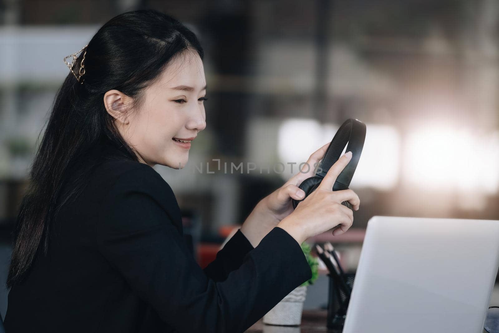 Concept of taking a break from work, an accountant or a female company employee or a business owner is using headphones to listen to music to relieve stress and fatigue from work. by Manastrong