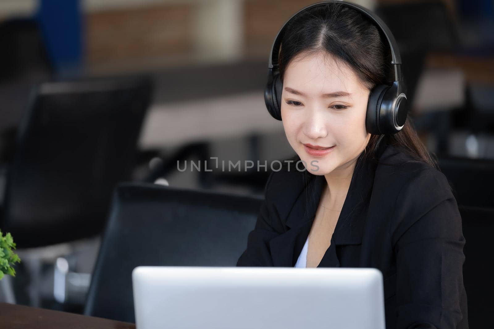 Concept of taking a break from work, an accountant or a female company employee or a business owner is using headphones to listen to music to relieve stress and fatigue from work