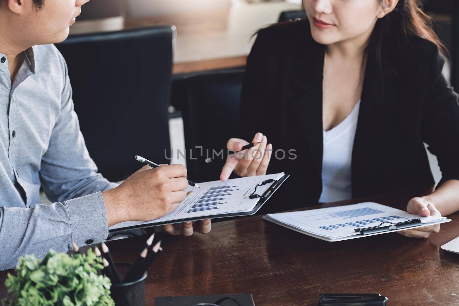 Teamwork concept, consultation, male economist holding pen pointing to budget, finance and investment documents, discussing and planning finances with female advisors in conference room