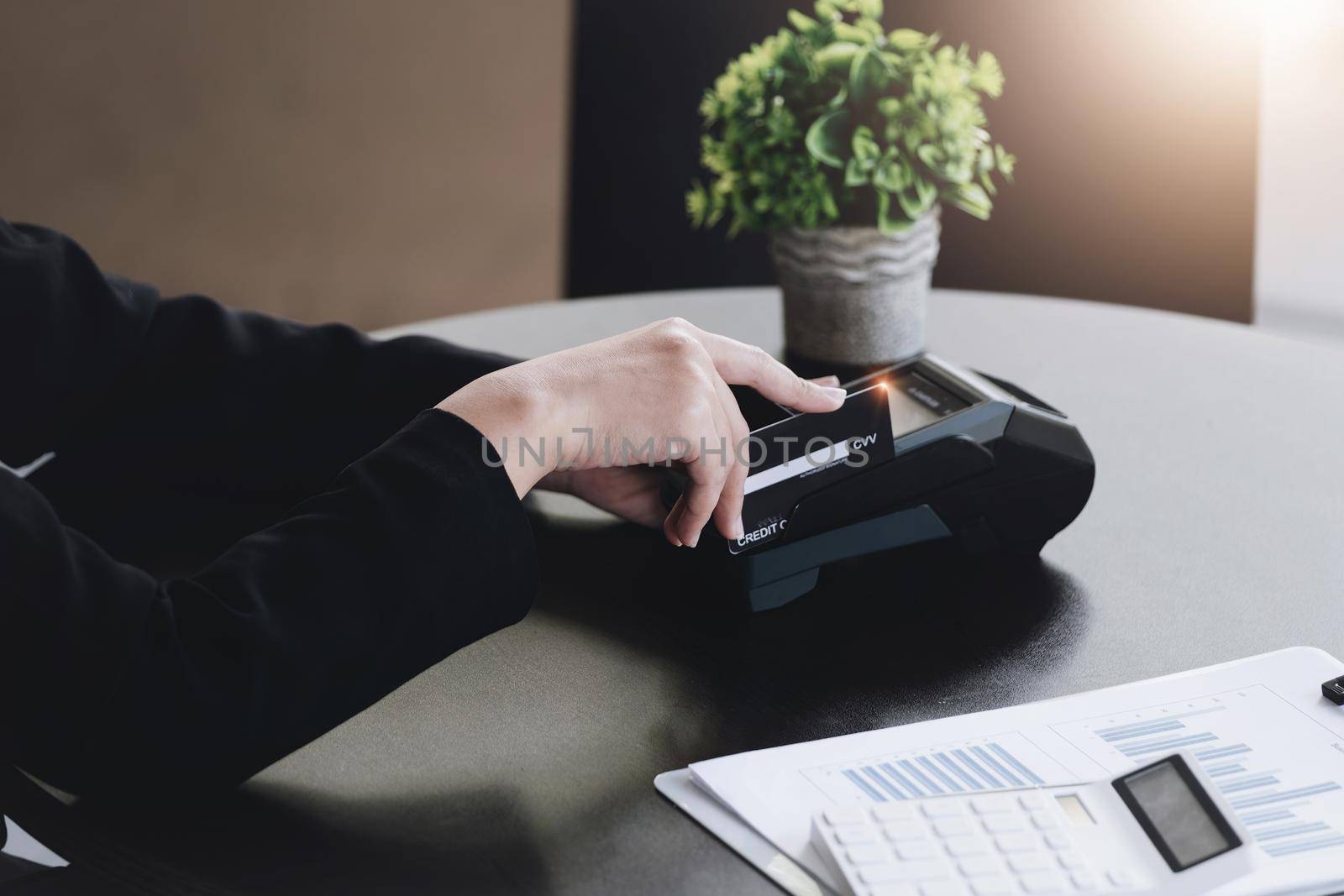 Safe technology concept from using credit card, employee is holding customer's credit card to pay for service or payment via electronic card swipe machine. by Manastrong