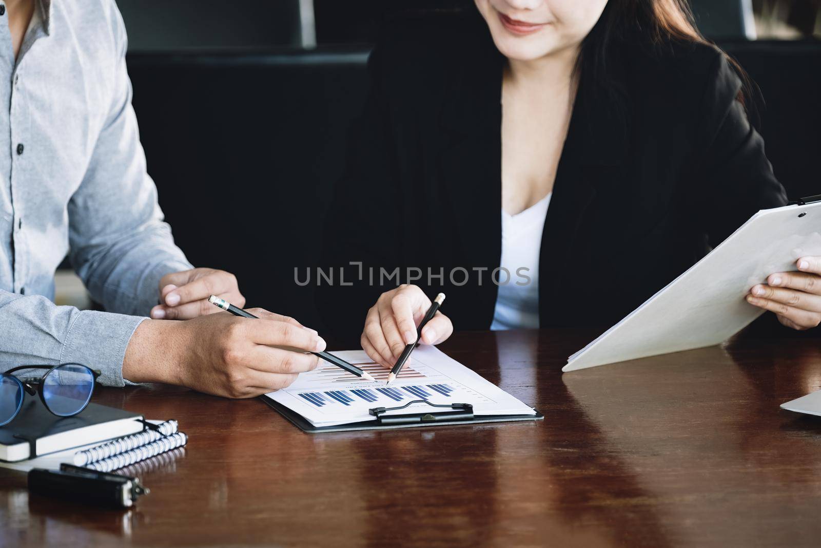 Teamwork concept, consultation, male economist holding pen pointing to budget, finance and investment documents, discussing and planning finances with female advisors in conference room. by Manastrong