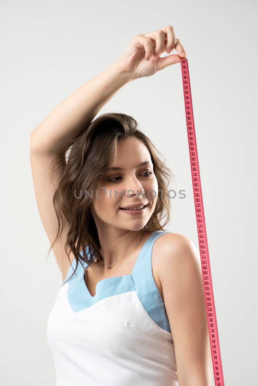 Young brunette fitness sporty sexy woman with pink measure tape on white background. Time for diet and slimming weight loss. Health care and healthy nutrition. by vovsht
