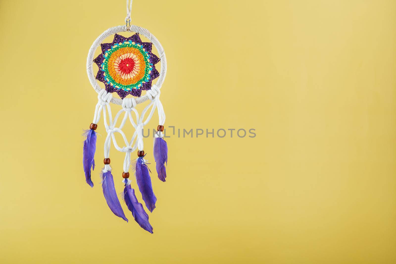 Handmade amulet dream catcher on a yellow background, protecting the sleeper from evil spirits and diseases