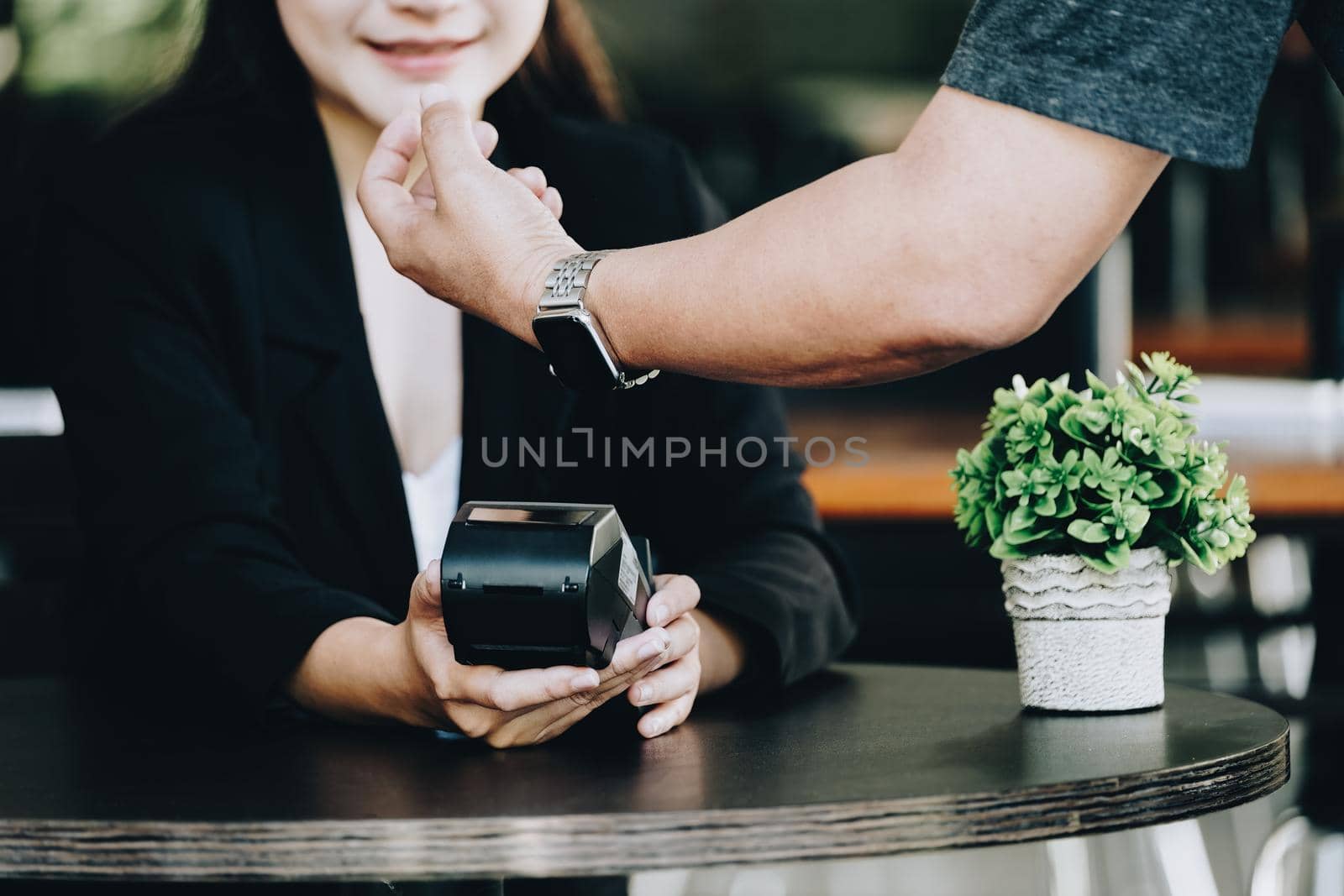 Payment security technology concept and service fees, Employees are holding electronic card machines for customers to use smartwatches to pay via paywave technology. by Manastrong