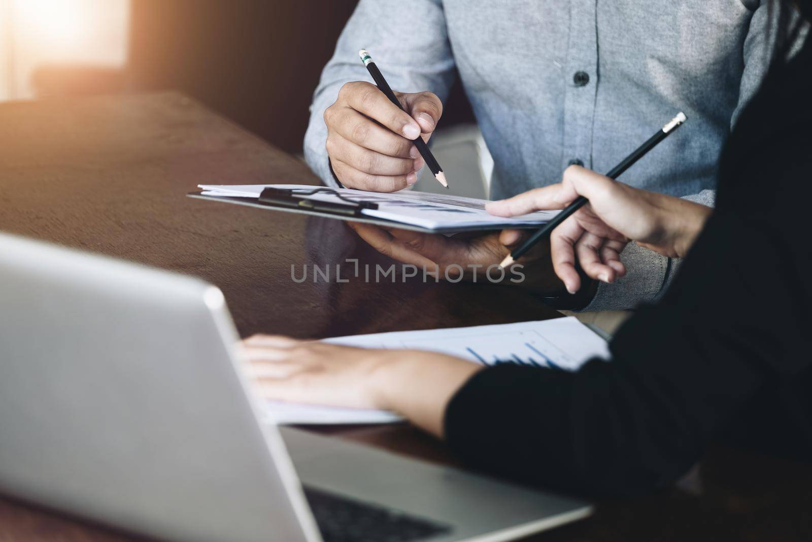 Teamwork concept, consultation, male economist holding pen pointing to budget, finance and investment documents, discussing and planning finances with female advisors in conference room. by Manastrong