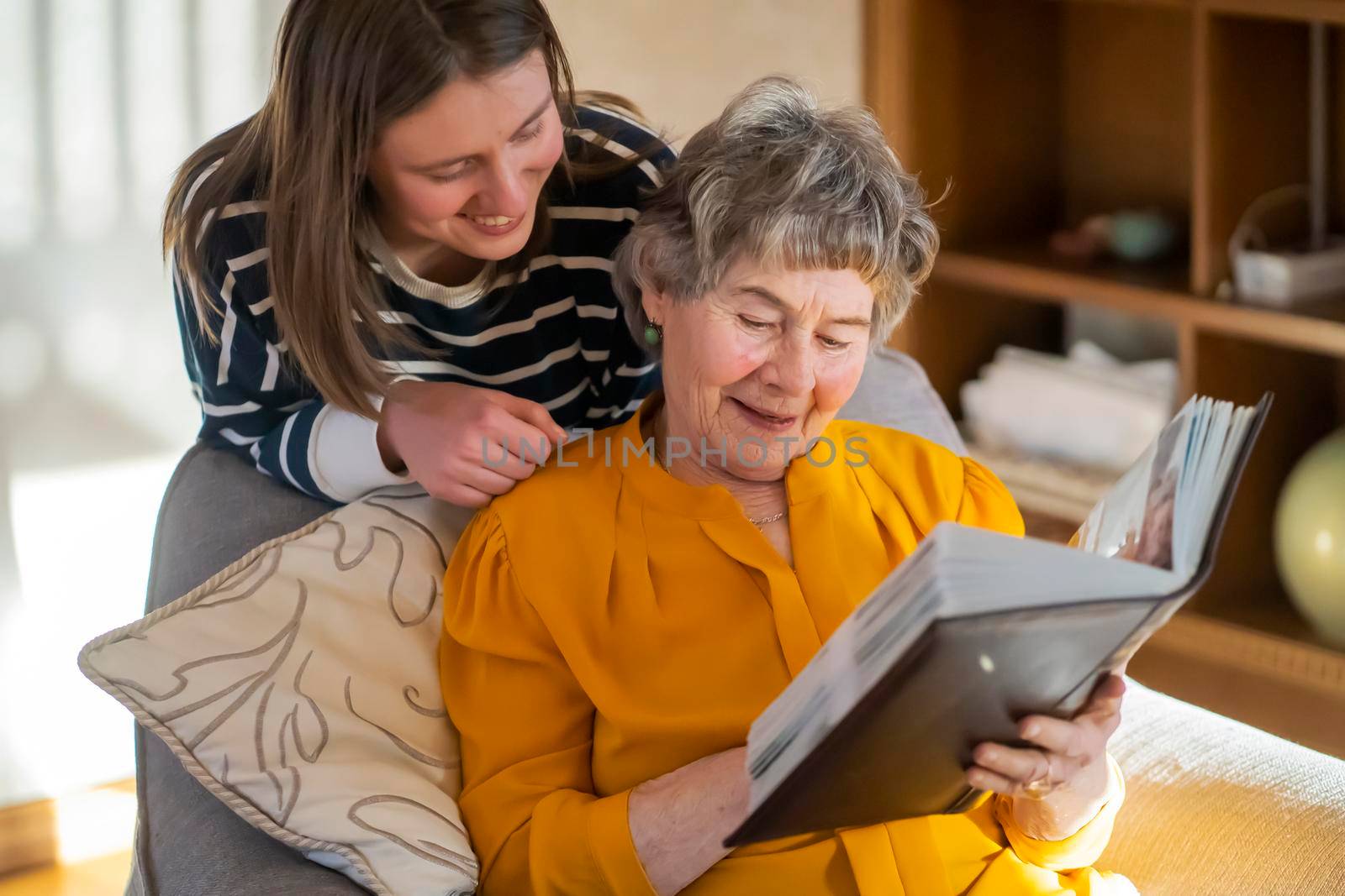 Grandmother and her young granddaughter spent great time together, family members look at photos from the youth of an elderly parent, through the pages of the album and recall funny stories from life.