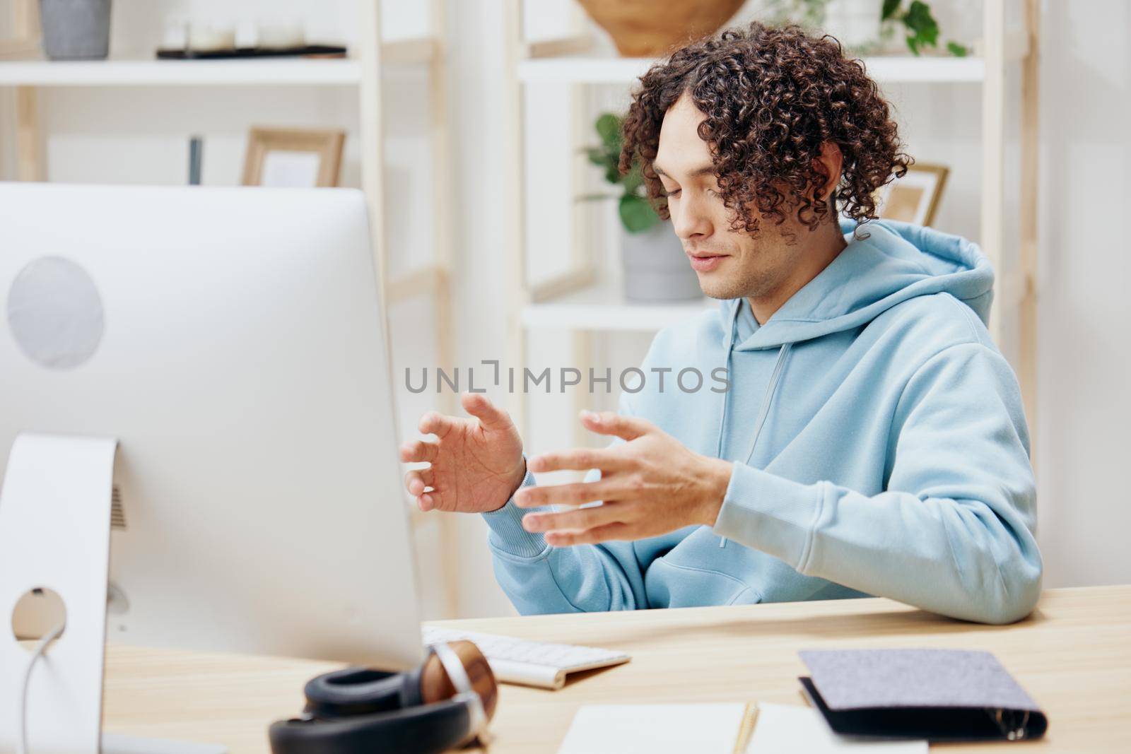 A young man sitting at a table in front of a computer freelance interior. High quality photo