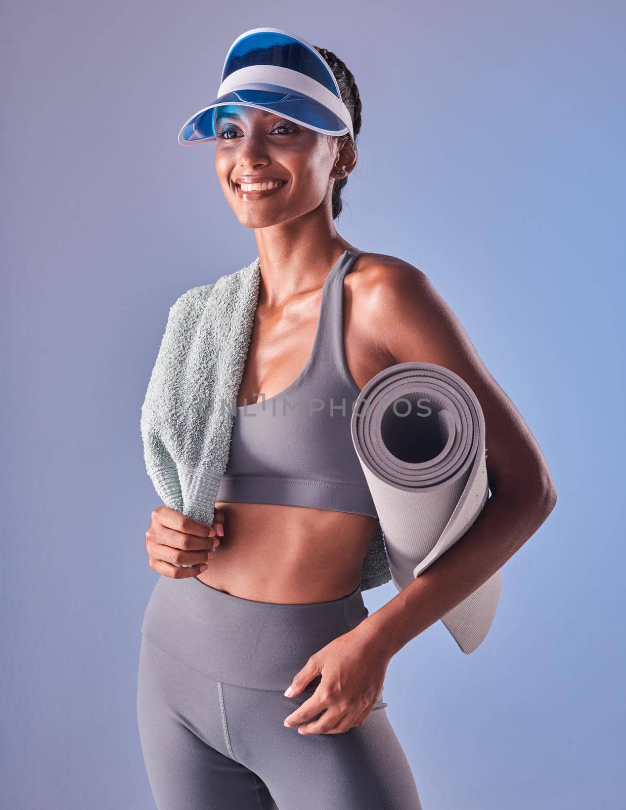 The greatest pleasure of life is good health. Studio shot of a fit young woman holding a towel and exercise mat against a grey background. by YuriArcurs