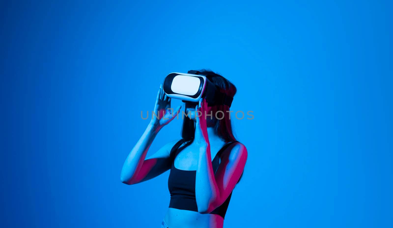 Smile happy woman getting experience using vr-headset glasses of virtual reality much gesticulating hands on gray background. Girl spend shes time in metaverse. by vovsht