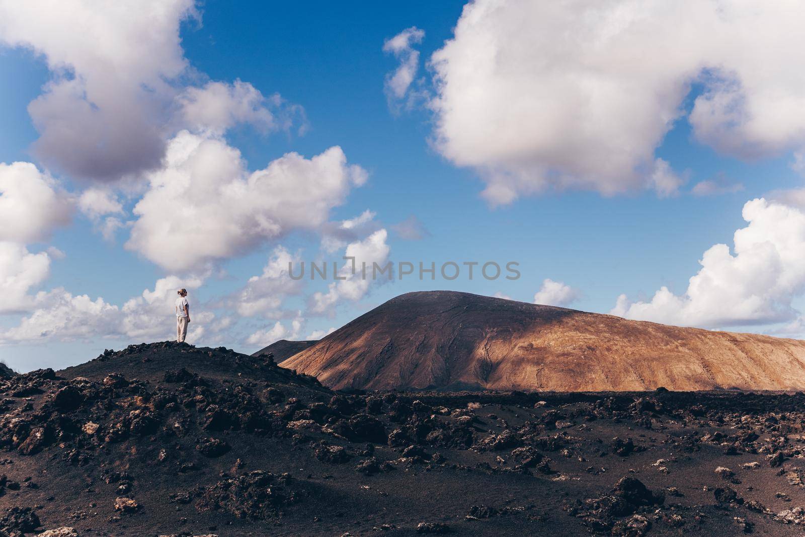 Female tourist enjoying amazing views of volcanic landscape in Timanfaya national park on Lanzarote, Spain. Freedom and travel adventure concept