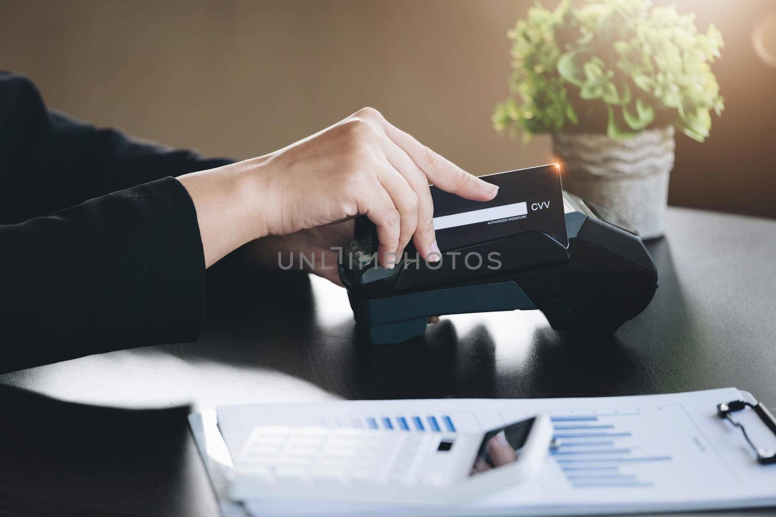 Safe technology concept from using credit card, employee is holding customer's credit card to pay for service or payment via electronic card swipe machine. by Manastrong