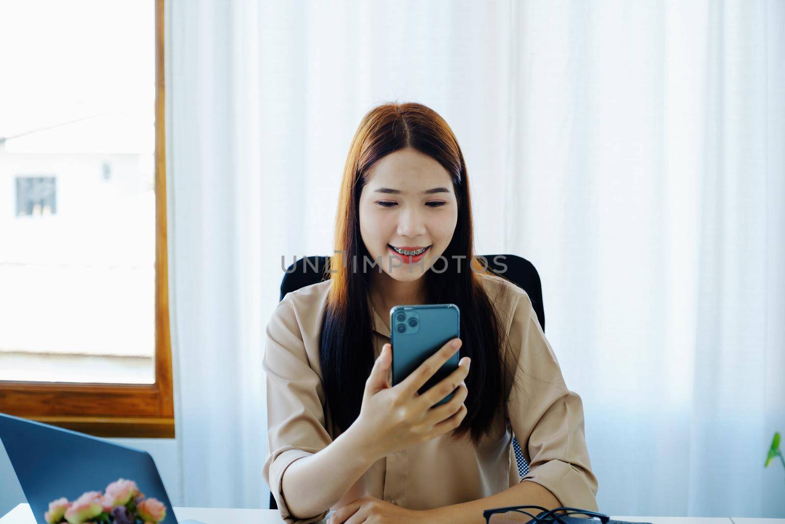 Chat, social distancing, tech communication, Asian female company employee using smartphone mobile video conference call with colleagues for a meeting while sitting at home