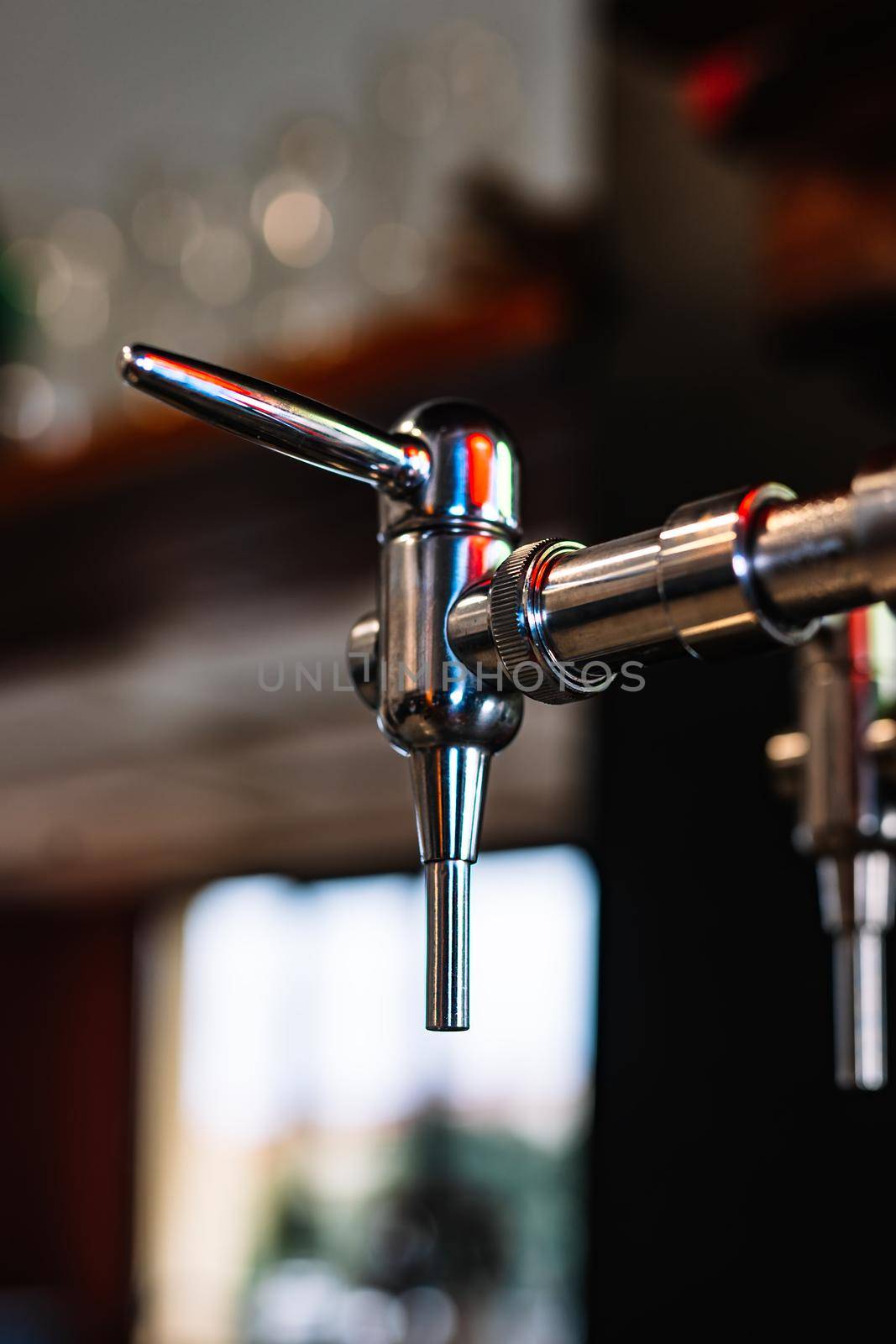 detail of beer dispenser. Apparatus for dispensing beer in the bar. Restaurant. warm atmosphere and dim light. Light reflected on beer dispenser.