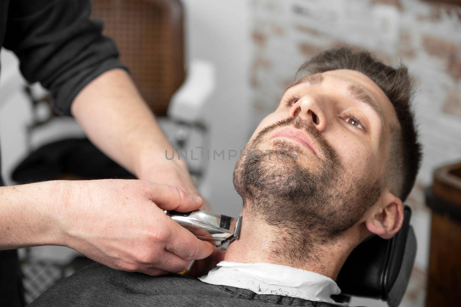 Professional barber cutting beard of handsome man by HERRAEZ