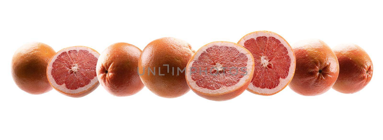 Whole and cut grapefruits levitate on a white background.