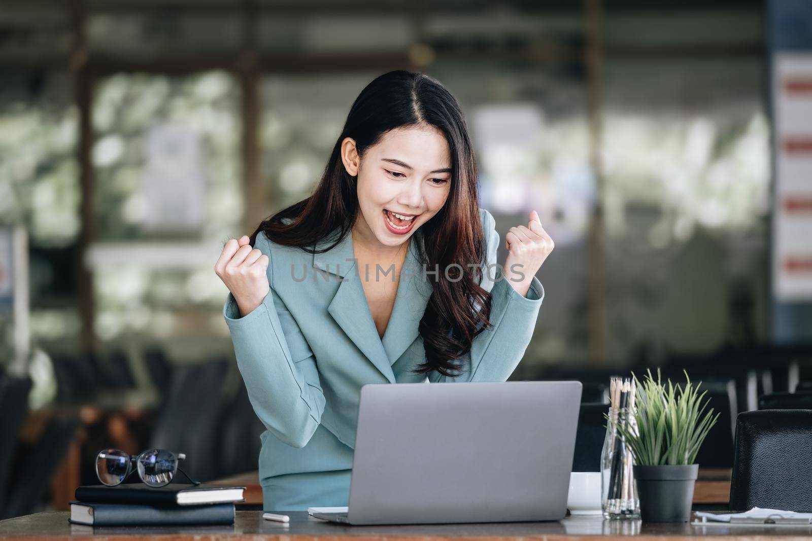 Business finance and investment, a business woman expresses happiness after successfully investing in the stock market on the Internet through a computer placed on a desk. by Manastrong