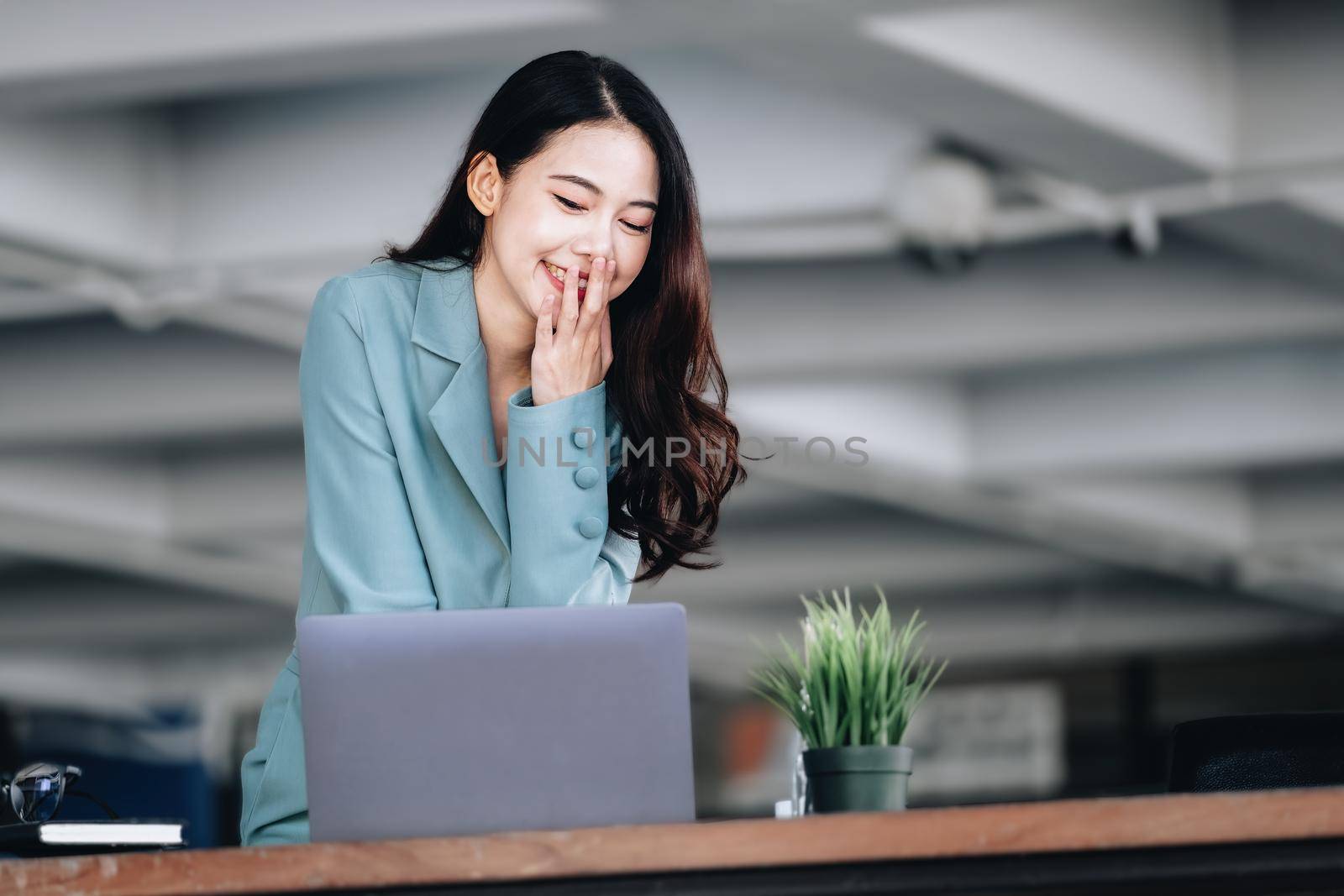 Business finance and investment, a business woman expresses happiness after successfully investing in the stock market on the Internet through a computer placed on a desk