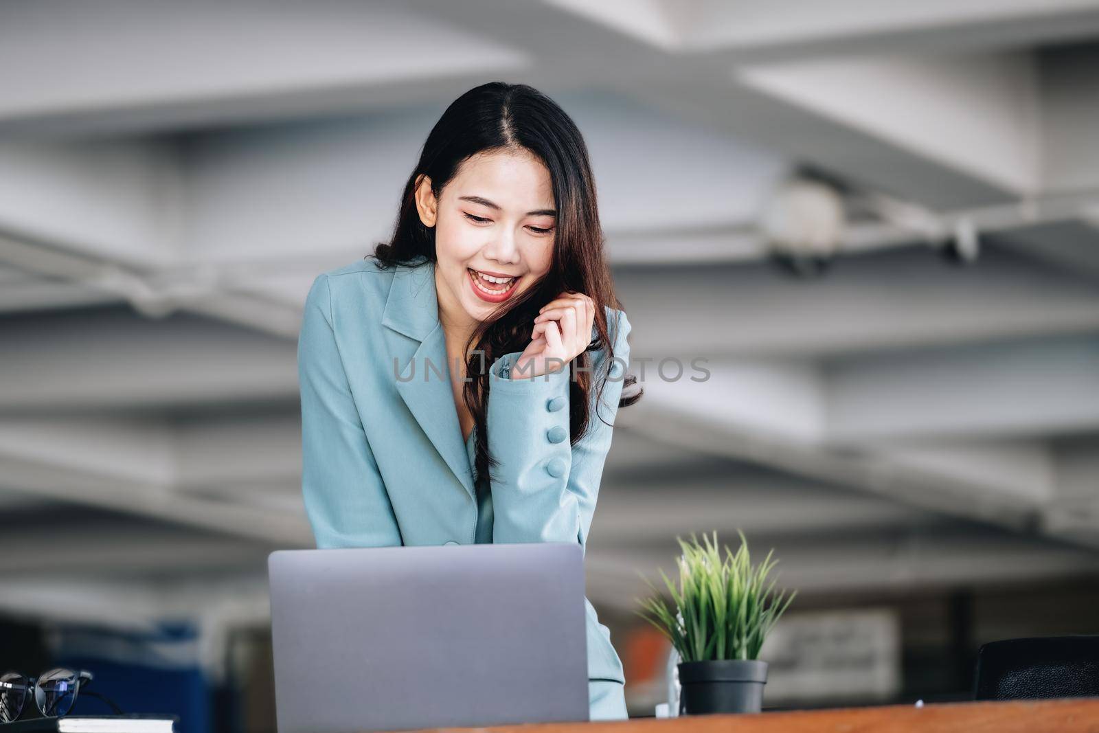 Business finance and investment, a business woman expresses happiness after successfully investing in the stock market on the Internet through a computer placed on a desk. by Manastrong