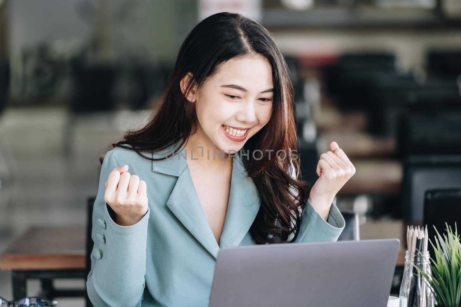 Business finance and investment, a business woman expresses happiness after successfully investing in the stock market on the Internet through a computer placed on a desk. by Manastrong