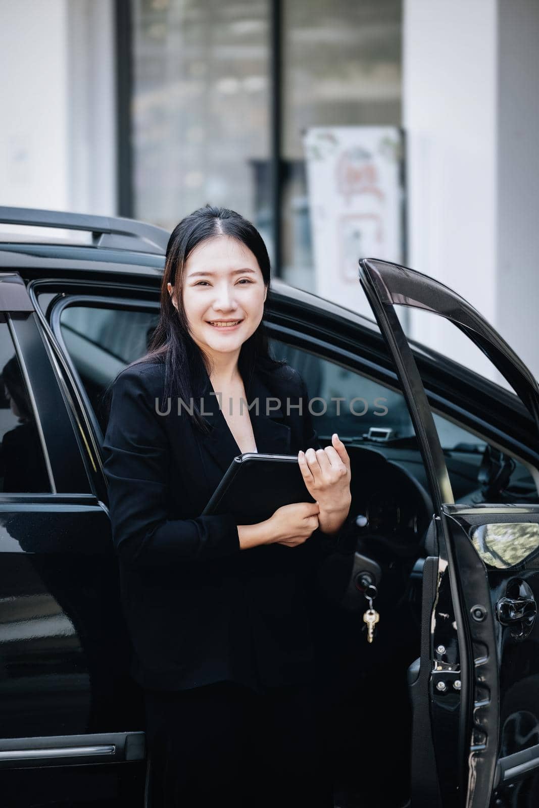 Asian businessmen, business owners, company presidents or female employees holding a tablet are getting out of the car to attend a business plan meeting at the meeting. by Manastrong