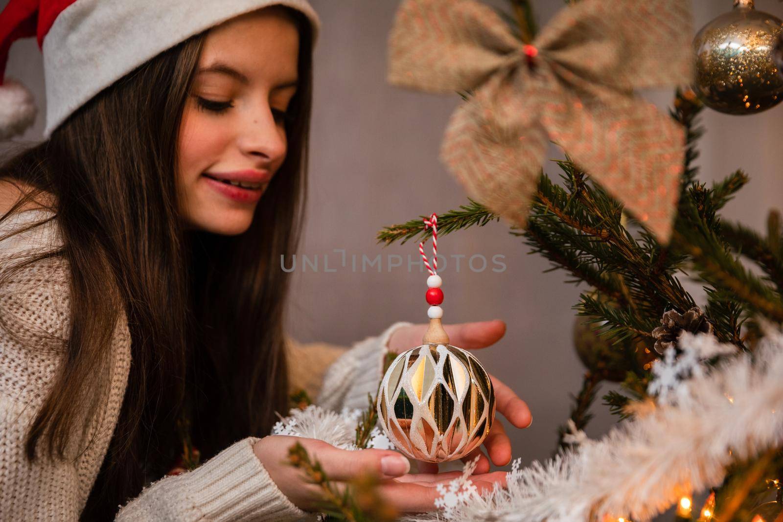 Long sleeves in cream sweater. Christmas tree bauble in delicate feminine hands. An annual Christmas decorating ritual in Poland.