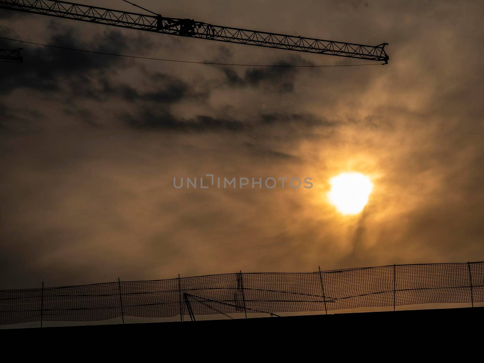 silhouette of a construction crane behind a sunset