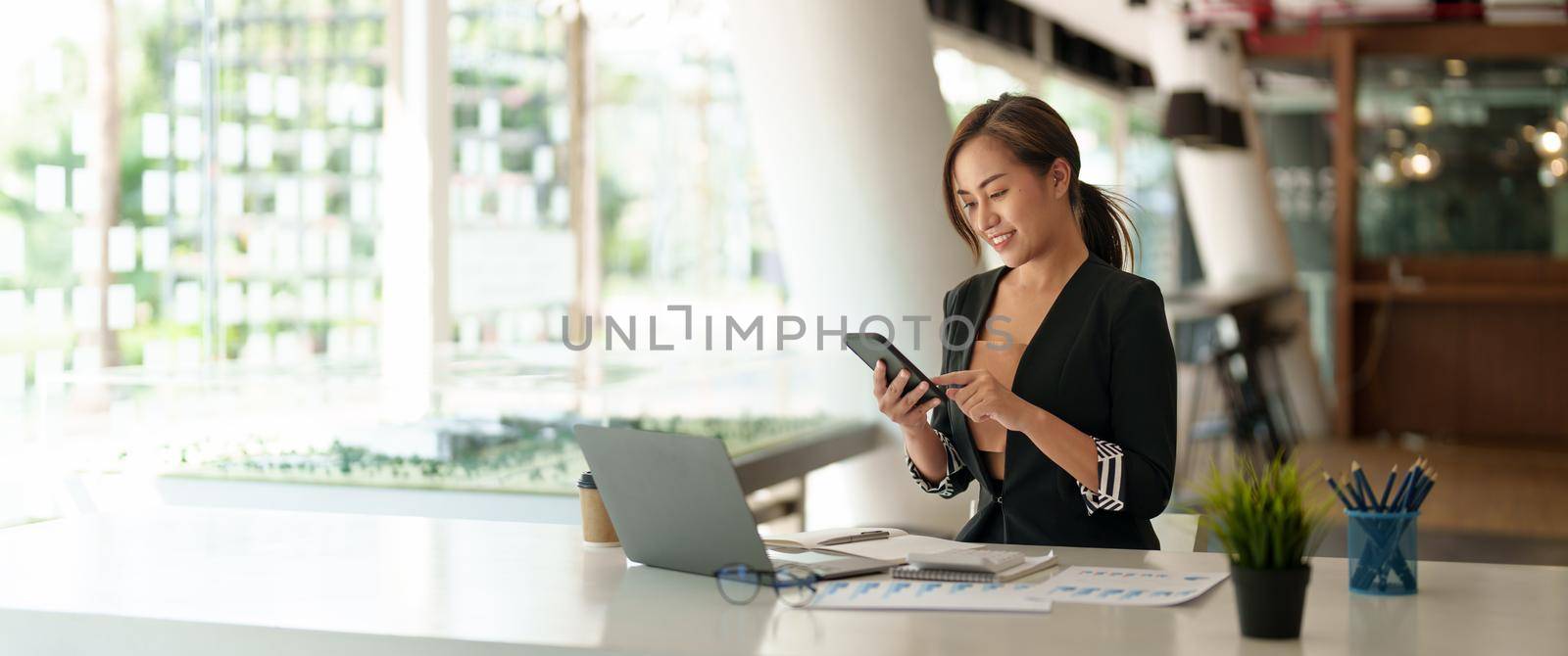 Business asian woman using mobile phone during checking an email or social media on internet. accounting financial concept. by nateemee