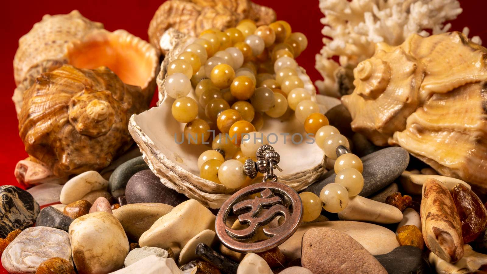 Buddhist prayer beads Mala are the conch shell on the sea rocks surrounded by sea shells. close-up by lempro