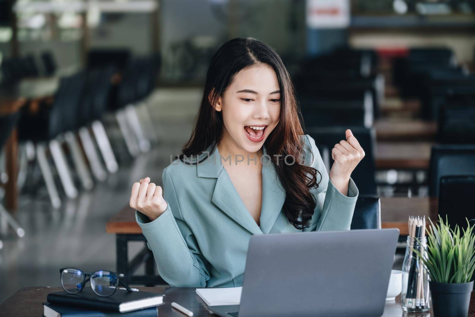 Business finance and investment, a business woman expresses happiness after successfully investing in the stock market on the Internet through a computer placed on a desk