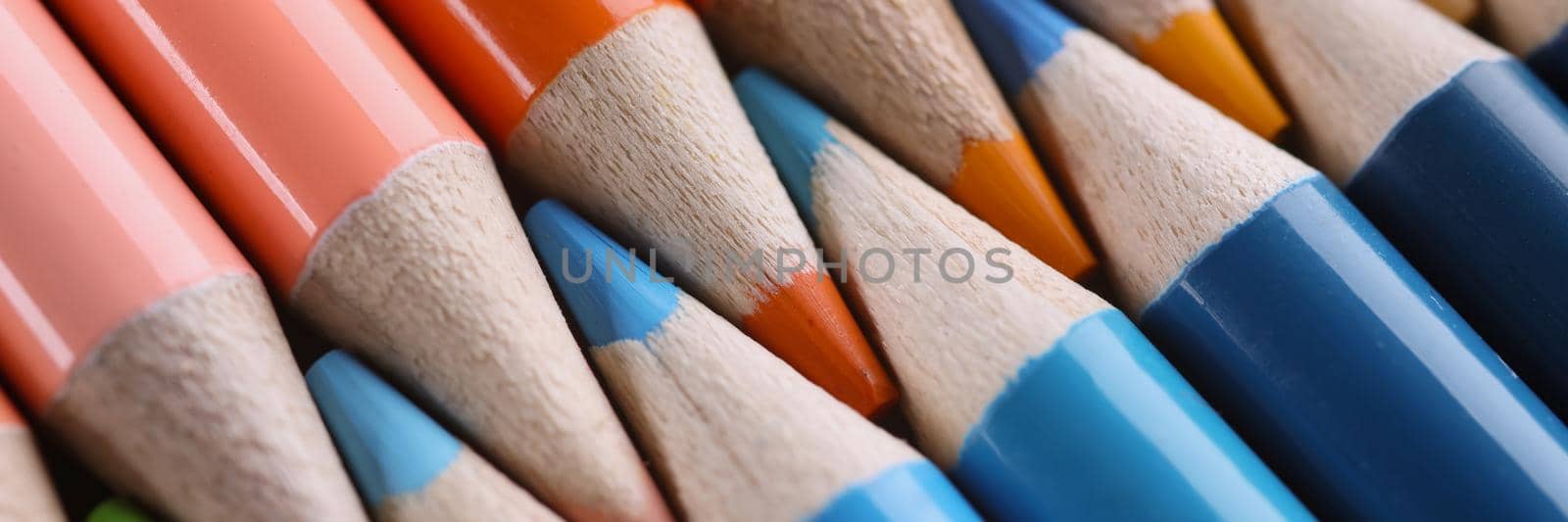 Close-up of multi colored pencils for drawing placed horizontally with tips to each other, group of tools for painting, shades of orange and blue. Art, design, creativity, hobby concept