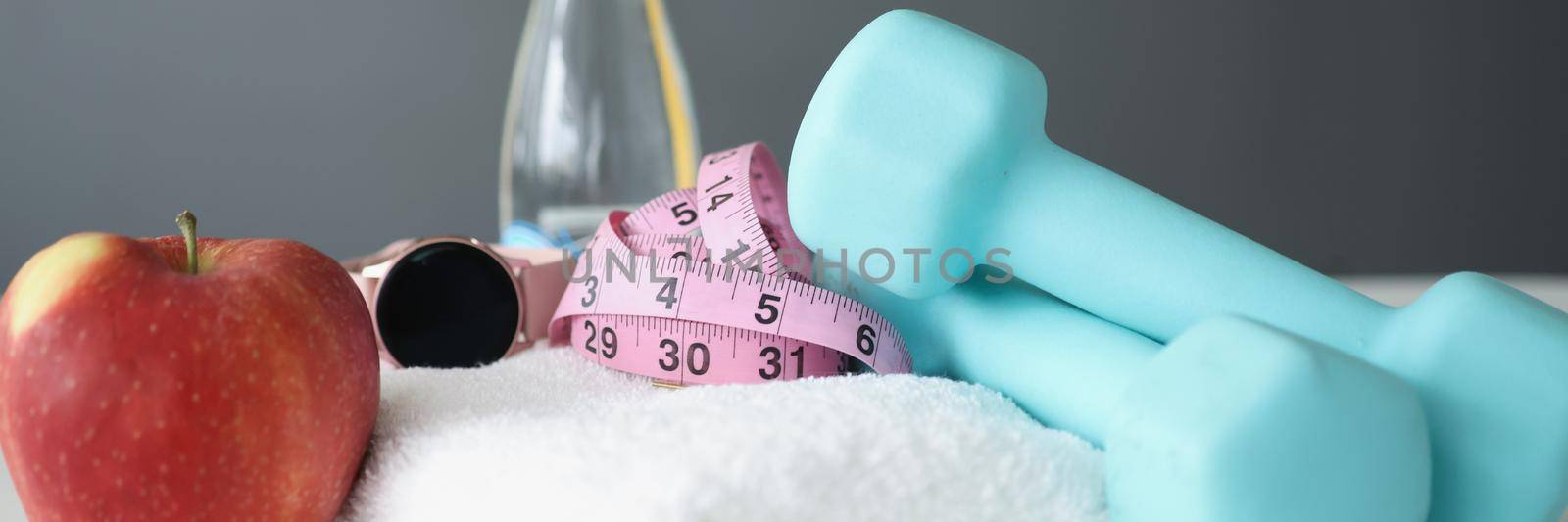 Close-up of healthy set, dumbbells, towel, water, apple, tape measure. Monitor your weight loss, physical activity and body change. Sport, active lifestyle, clean eating concept