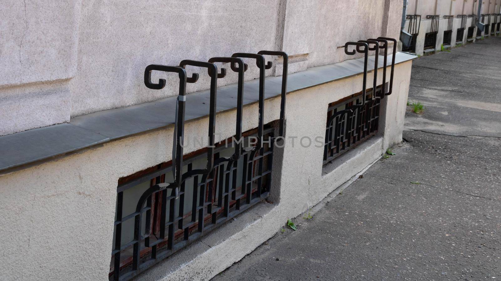 Wrought iron patterned grilles are installed outside on the first floor windows of the apartment building for safety