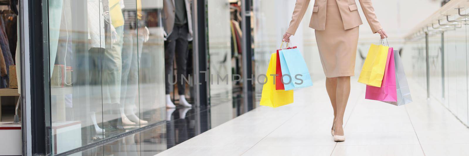 Portrait of smiling happy woman walking through mall with purchases. Attractive young shopper after lucky shopping day. Fashion and buying gifts concept