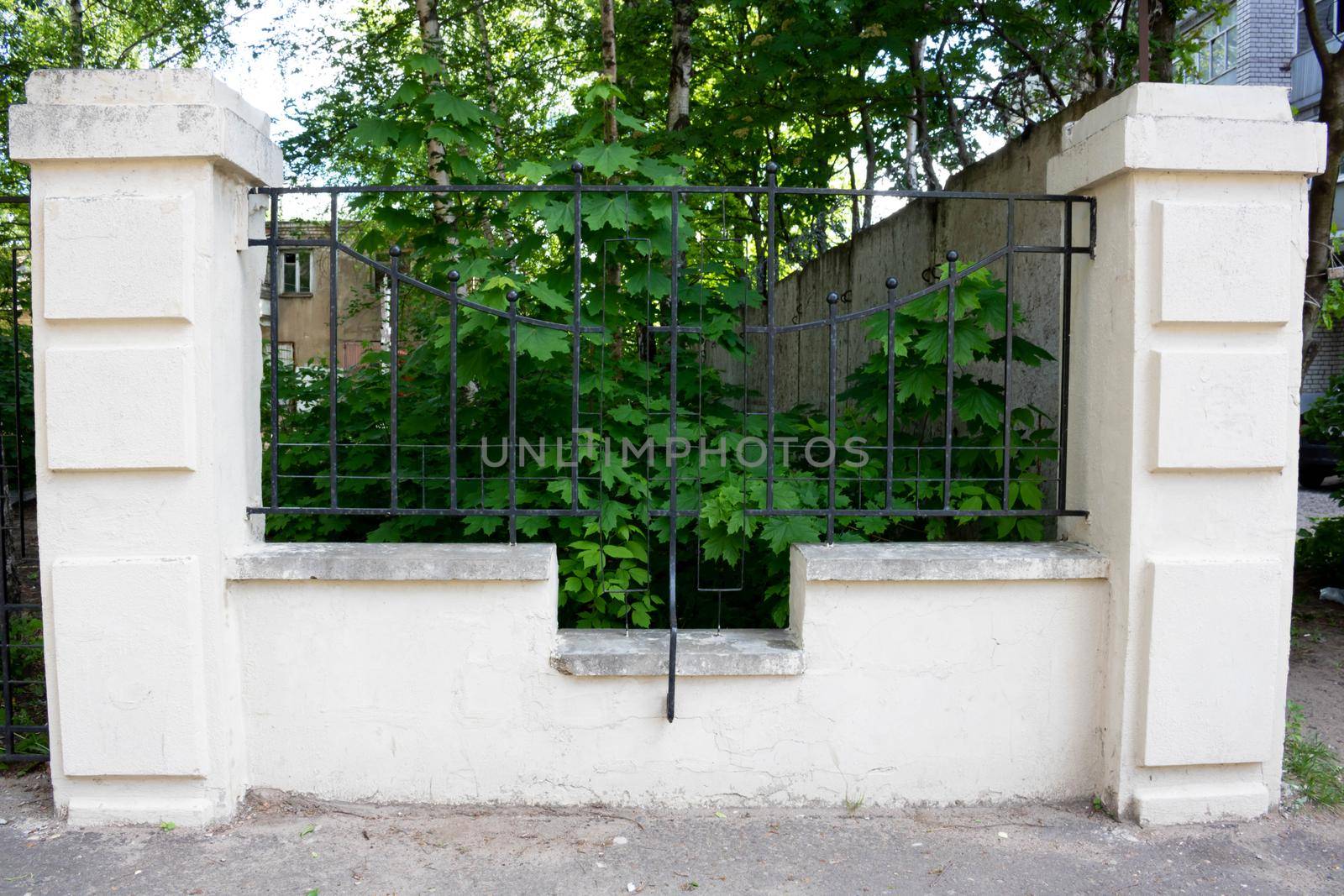 Black wrought iron fence between stone pillars by lapushka62