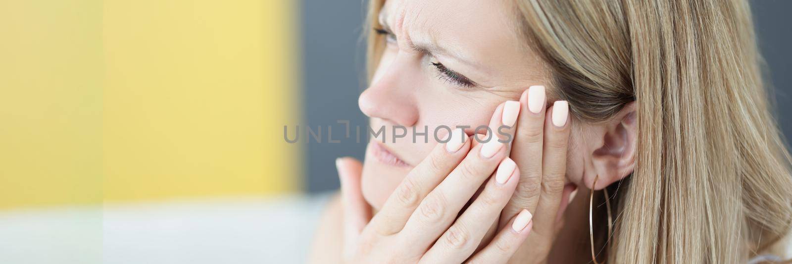 Portrait of beautiful young woman suffering from tooth pain, hold hand near cheek, feeling unwell because of tooth decay or sensitivity. Dental problem, healthcare, toothache concept